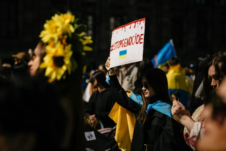 several people protesting in front of a building while one woman is holding up a sign