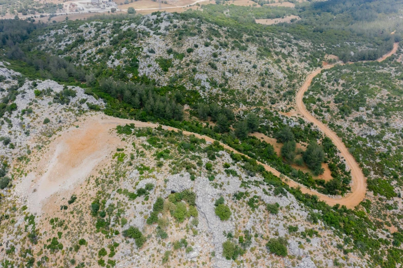 an aerial view of a dirt road winding into the mountains