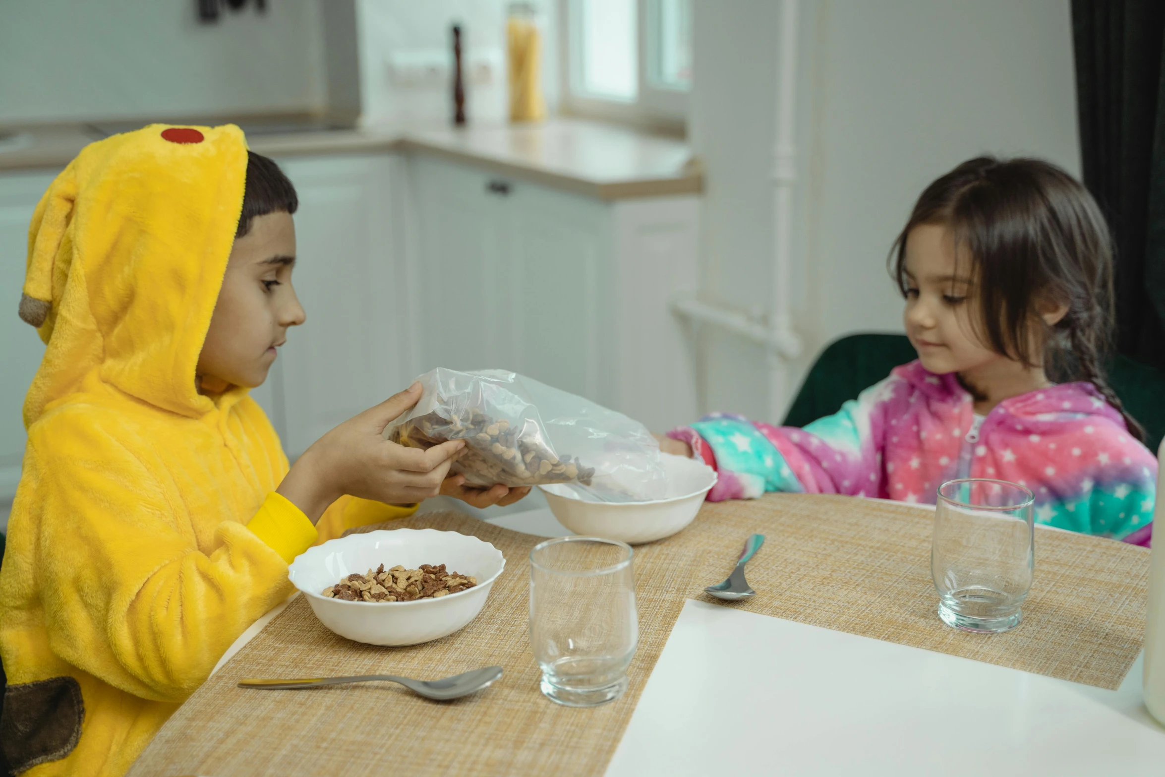 two s sitting at the table with their bowls of food