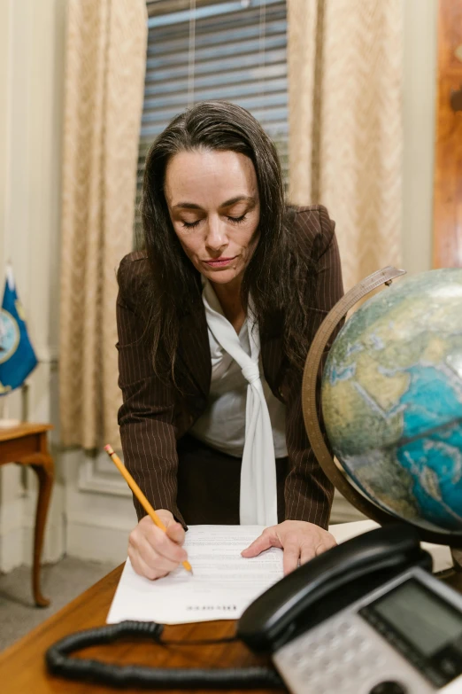 a woman looks at her writing paper near the phone