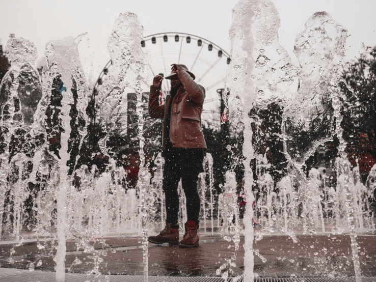 a girl stands at a fountain watching the world in front of her