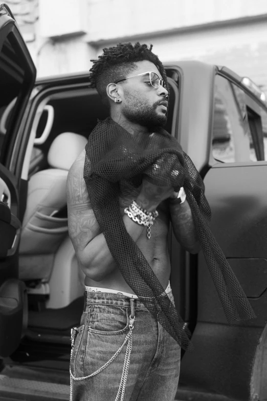 a man in glasses standing in front of a car