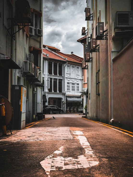 an empty alley has white buildings, dark clouds and light grey sky