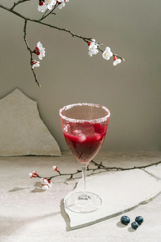 a drink in a wine glass garnished with cherries and leaves