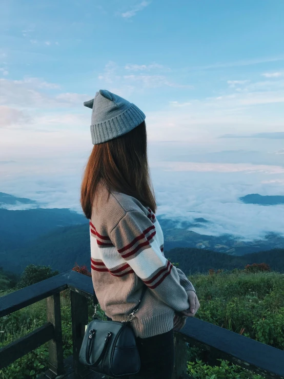 the girl sits on the wooden railing looking at the view