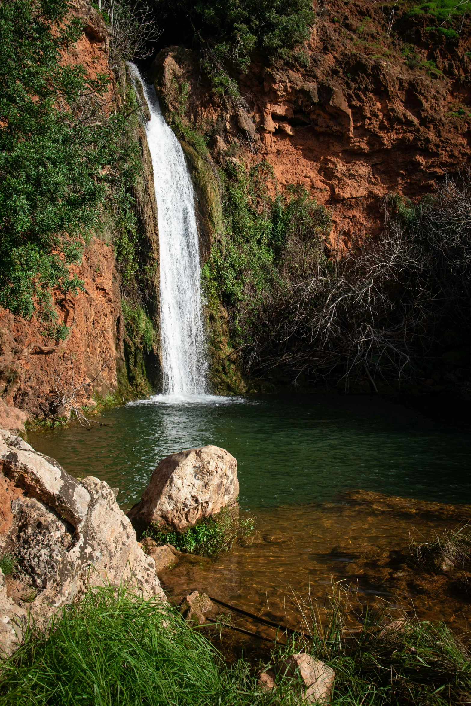 a man standing in the water beside a small waterfall