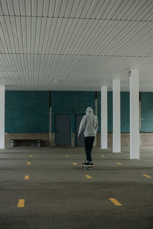 a person in grey sweatshirt riding a skateboard on an empty street