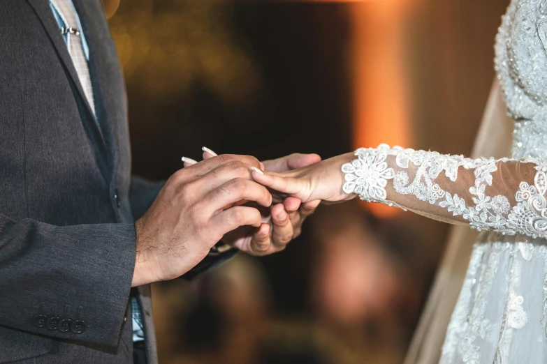 the bride and groom hold hands as they exchange rings at their wedding ceremony