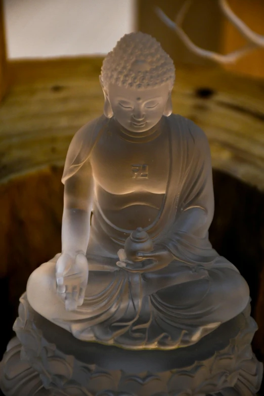 a light - up buddha statue is sitting on top of a piece of wood