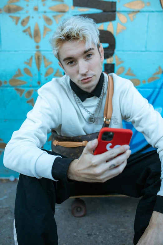 a boy is sitting on a skateboard and looking at his phone