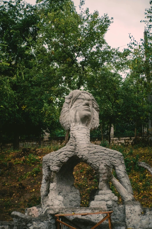 a statue sitting in the grass next to trees