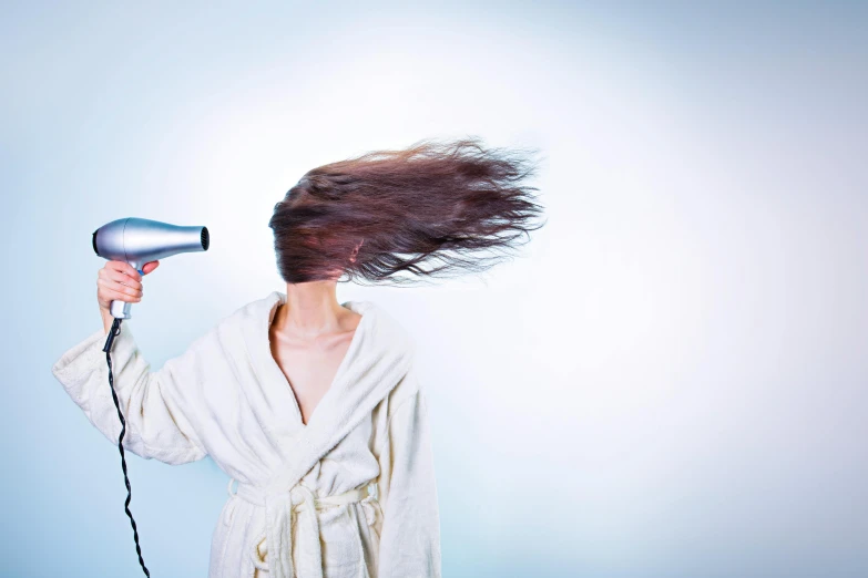 the woman is drying her hair with a blow dryer