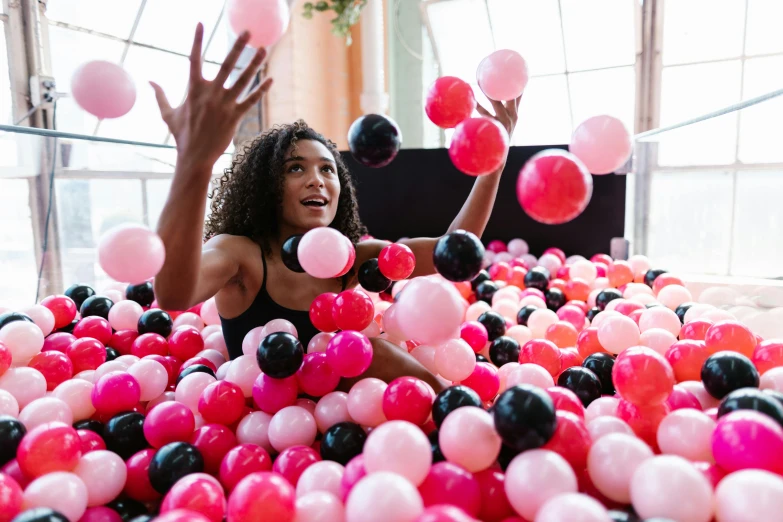 a woman wearing a black bathingsuit is surrounded by pink and black balloons