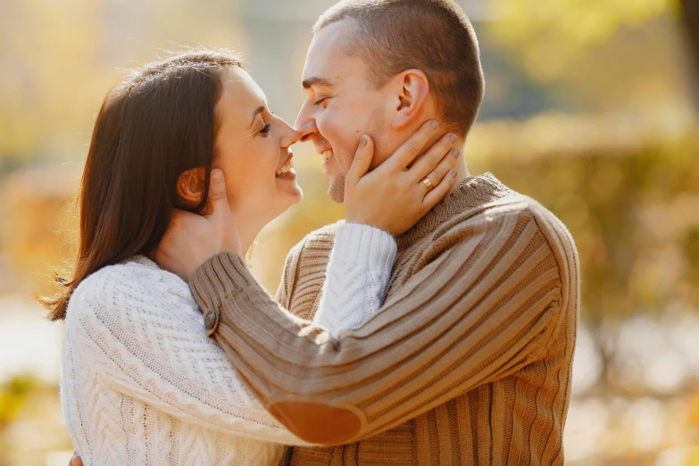 couple standing outside and kissing each other in autumn