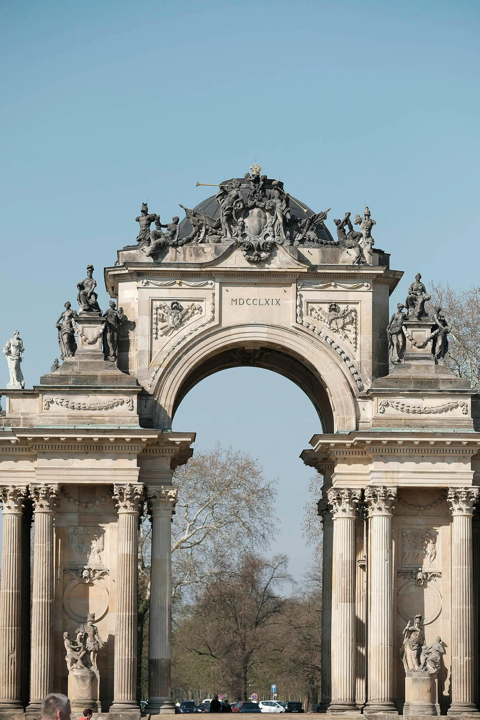 an arch in a park surrounded by statues