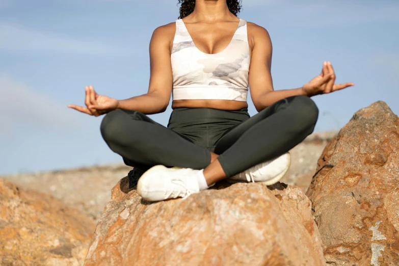 a woman is sitting on some rocks while meditating