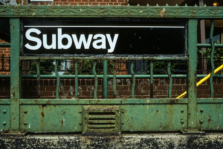 the subway sign is mounted on the outside of the train station