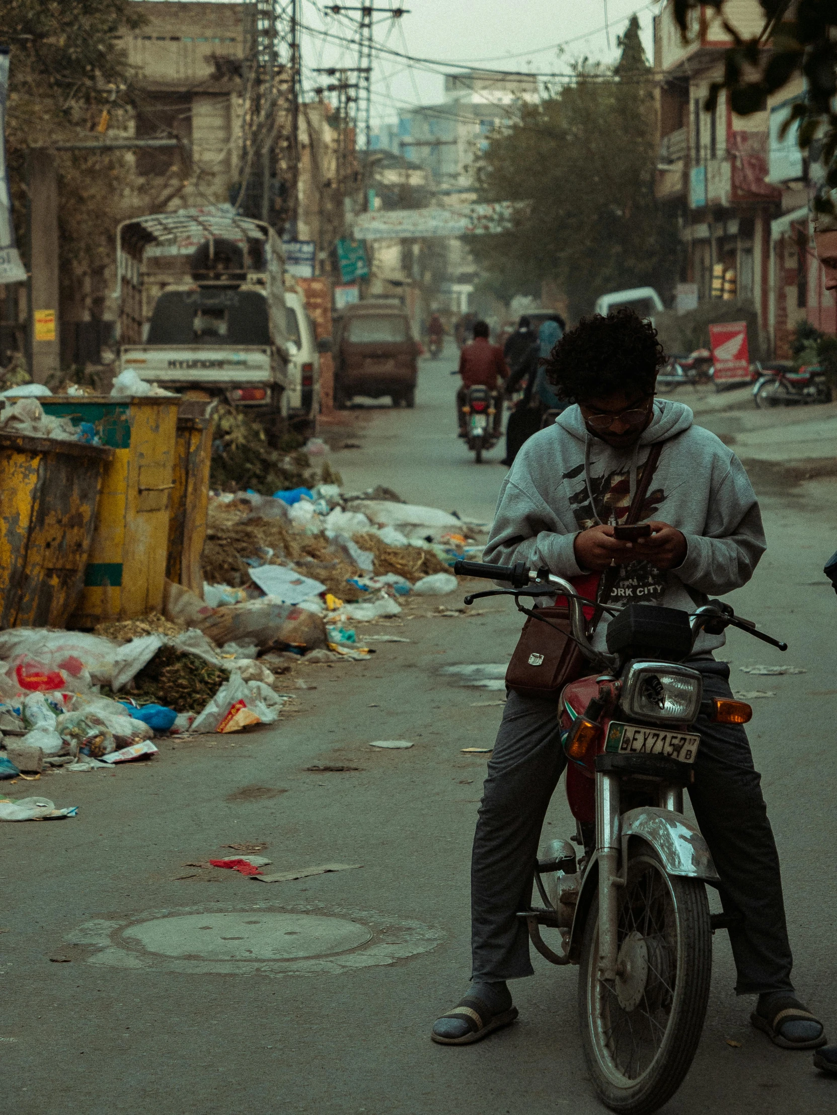 a man sits on his motor bike on a city street