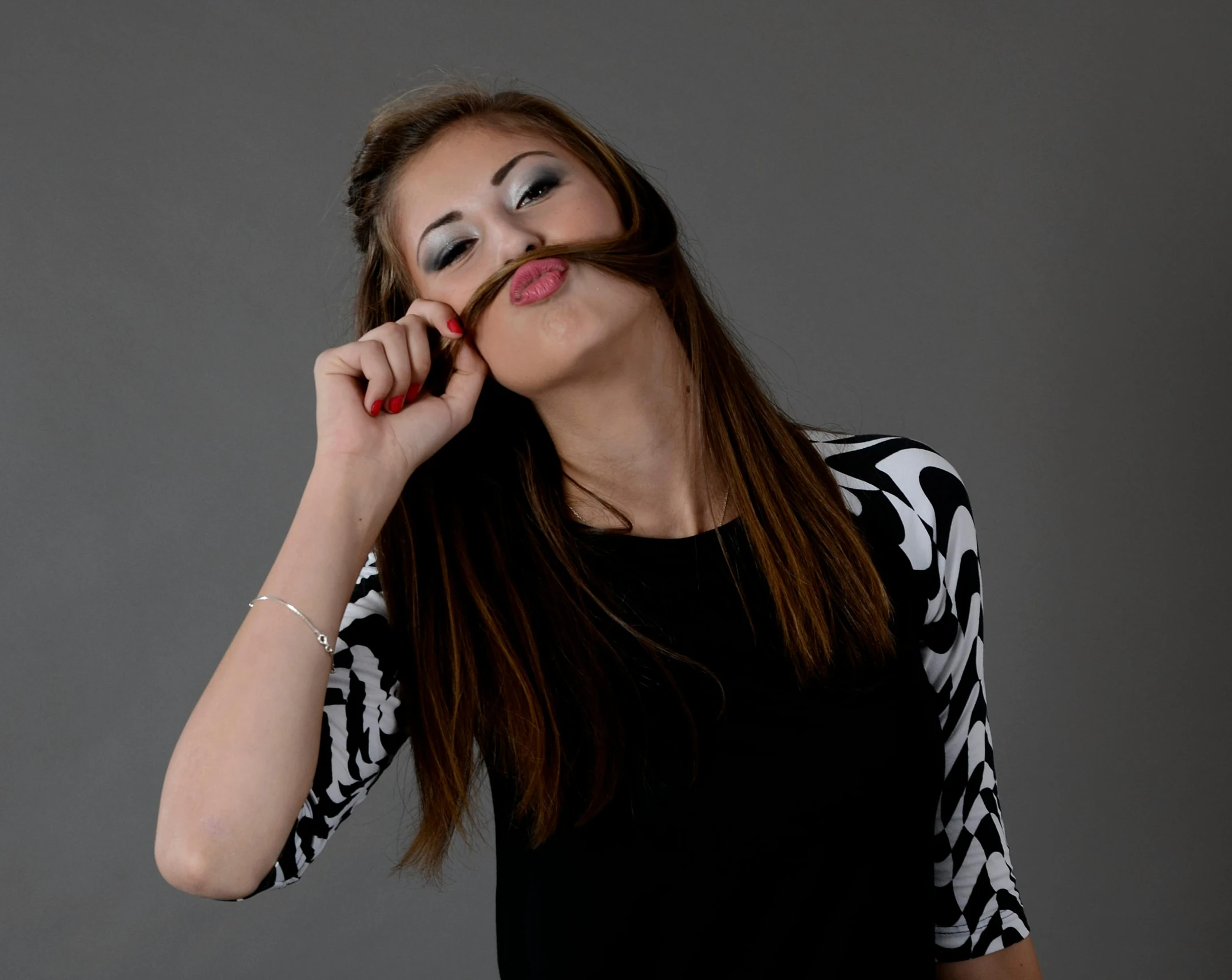 the girl in black top with white designs on her sleeve is posing with a hand on her mouth