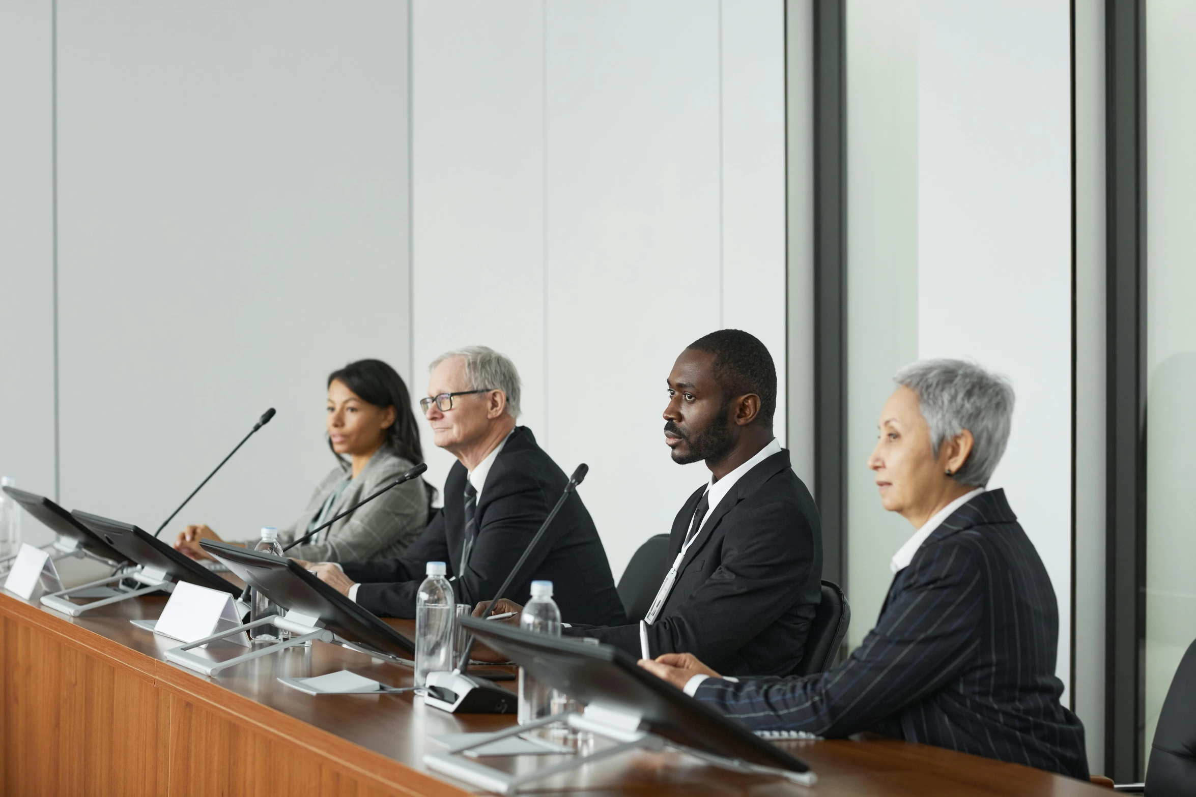 a group of people at a long table with their hands on the top of their heads