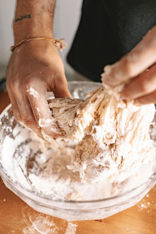 someone putting batter on top of a pizza dough