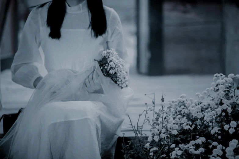 a woman in white dress sitting down near flowers