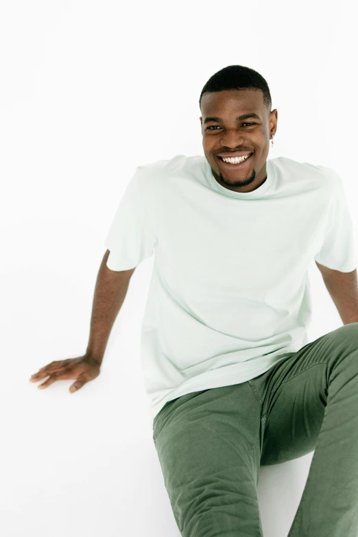 a black man wearing a white shirt sitting on top of a white floor