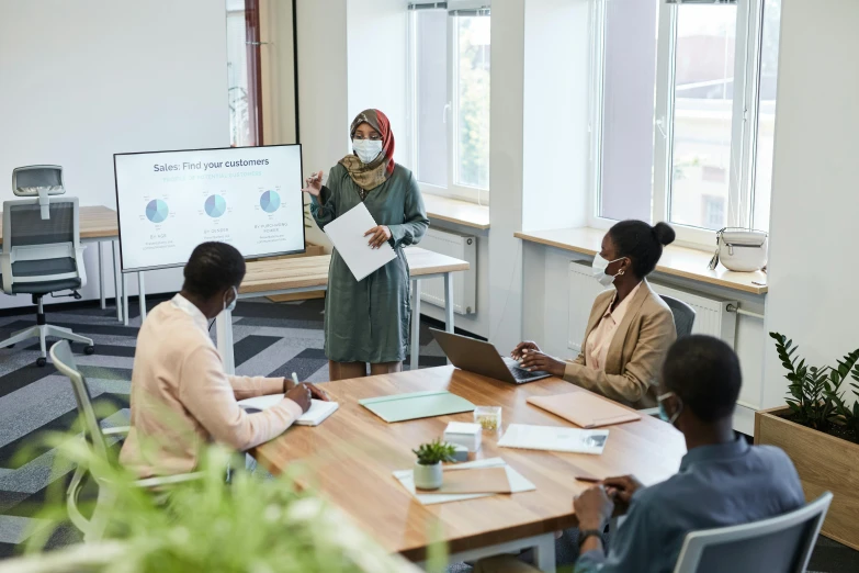 women in business attire sitting around a conference table talking