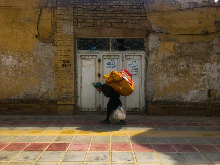 a person walking on a sidewalk with bags of luggage on their back