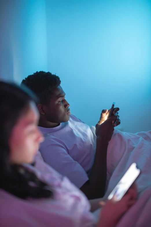 two people in bed playing a game on their phones