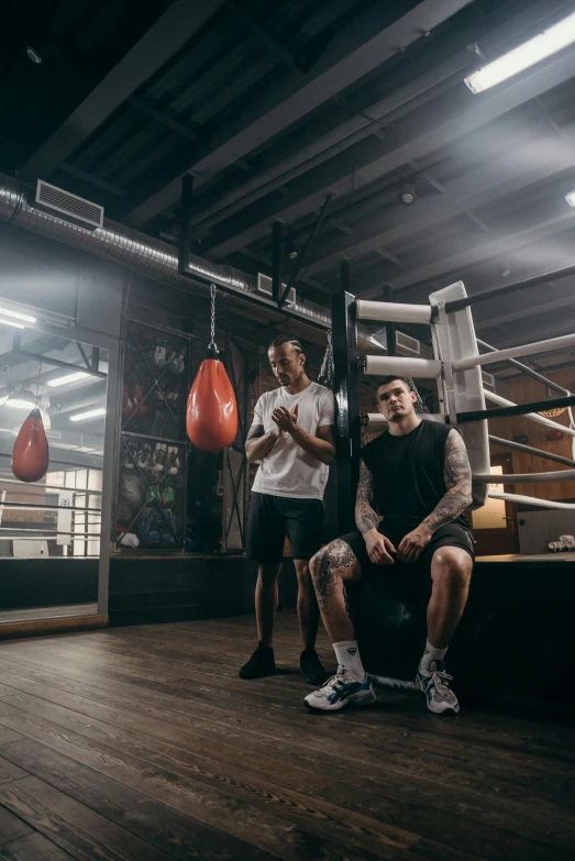 men are in a boxing ring, one holding an punching bag