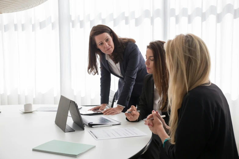 three women sitting around a table while one looks at the camera