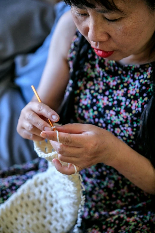 a woman holding onto a crochet hook while sitting on a couch