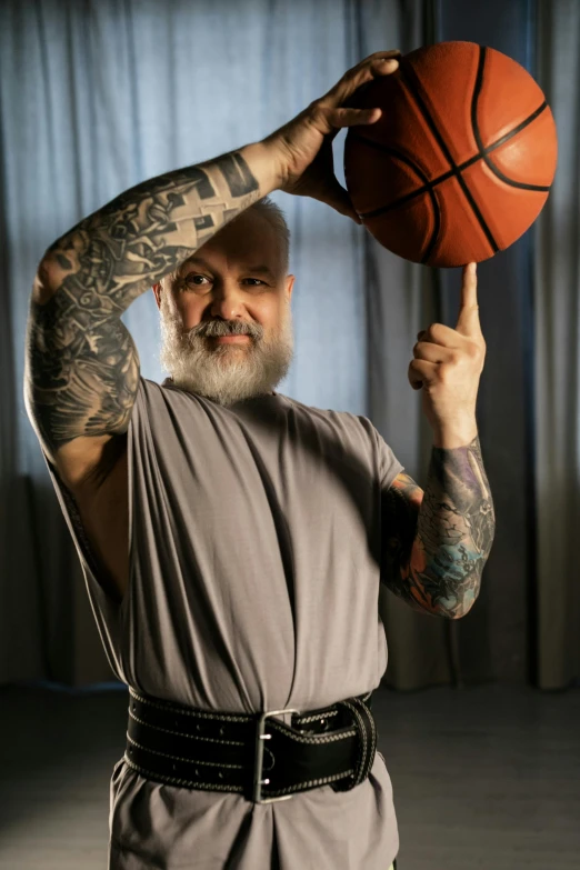 the man has tattoos holding a basketball on his shoulder