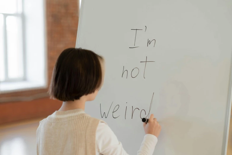 a little girl writing on a white board with a marker