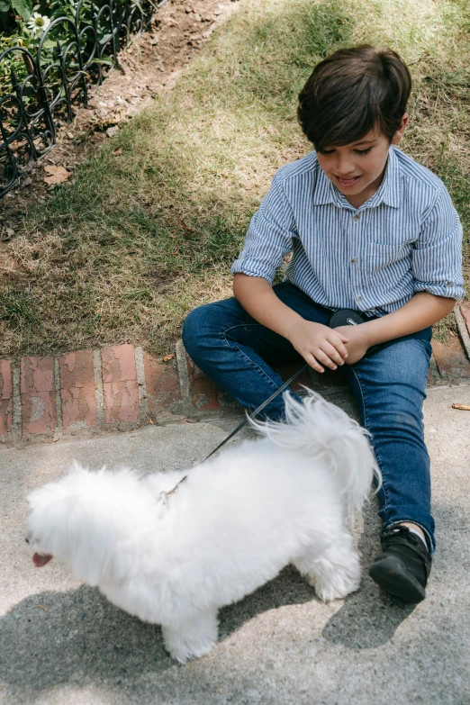 a  sitting on the curb petting a small white dog