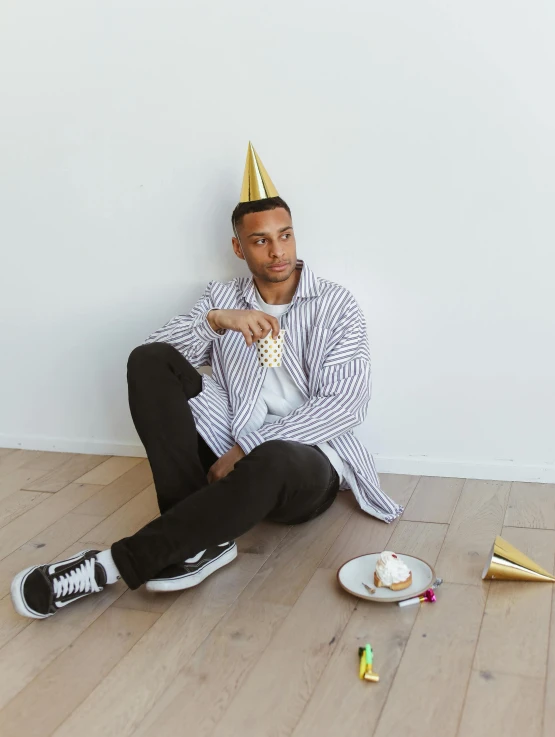 a man sitting on the floor in a party hat