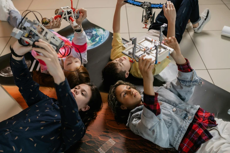 girls play with a small robot set made out of legos