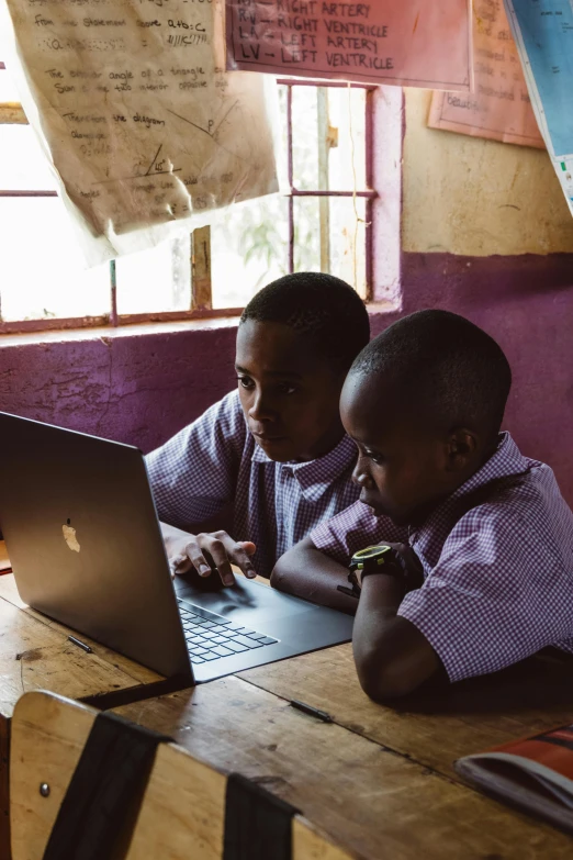 two small children using a laptop computer in a cafe