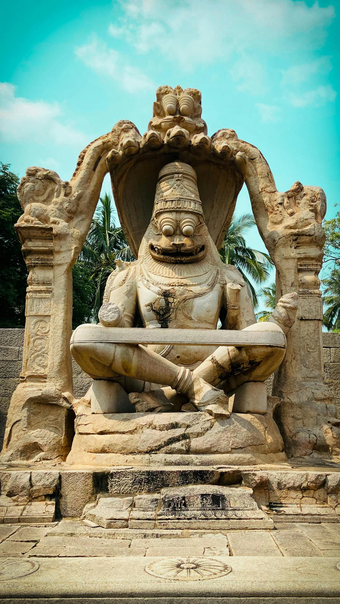 an old statue is sitting near a tall stone pillar