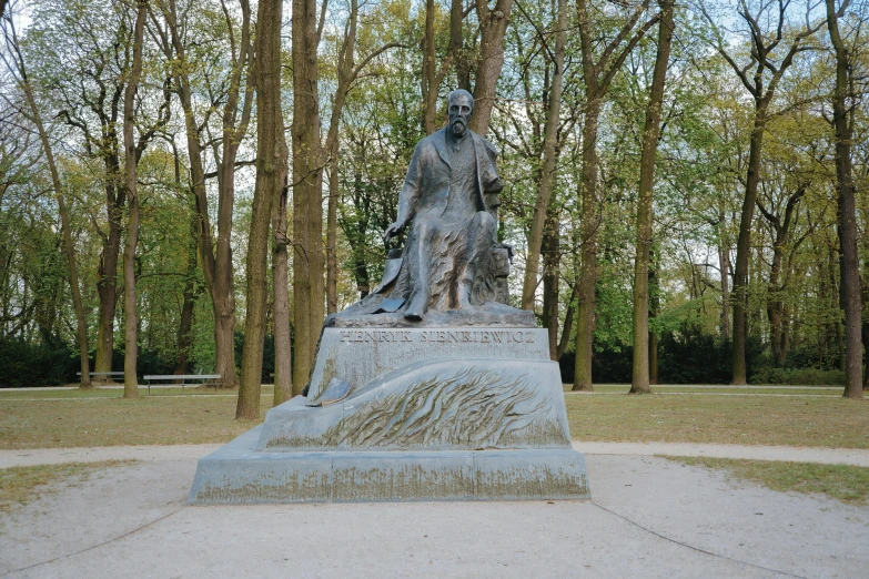a statue of a man sitting next to some trees