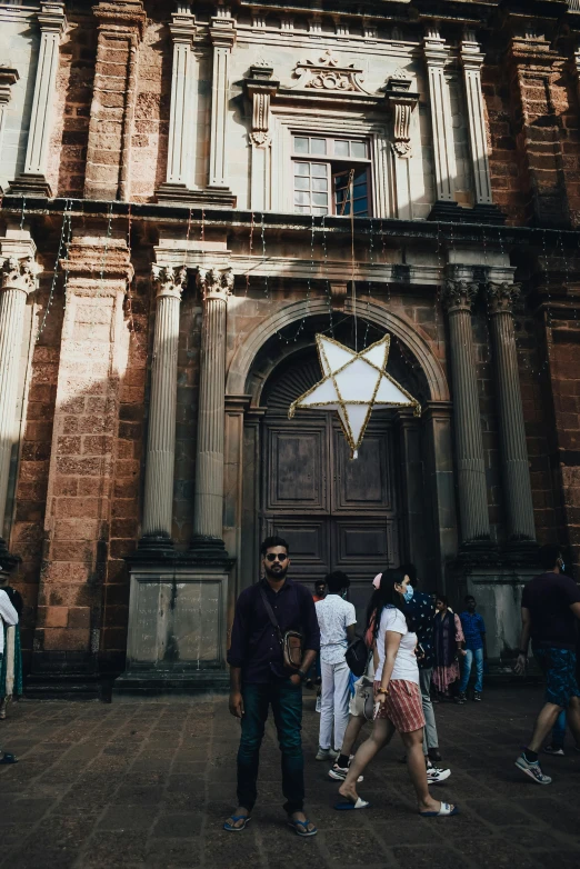 several people standing outside a building that has an over sized star on the door