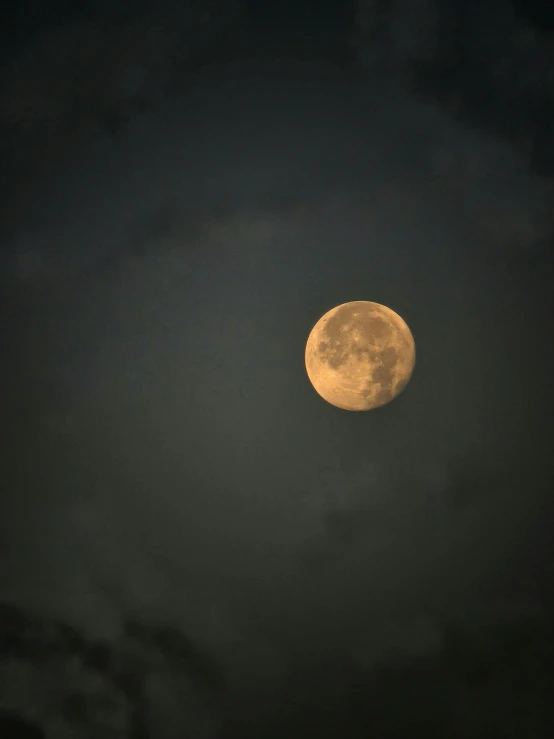 the moon is partially obscured by the clouds