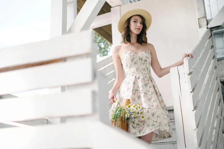 a beautiful young woman standing on steps wearing a dress and hat