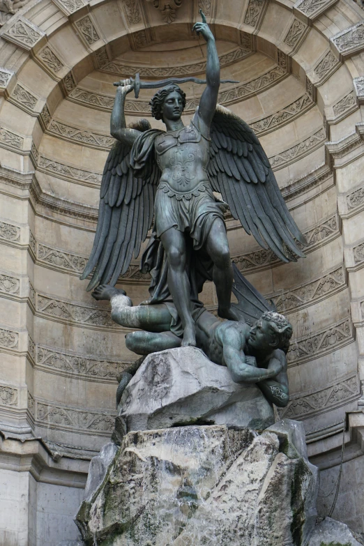 a statue with large wings sitting on top of a stone slab