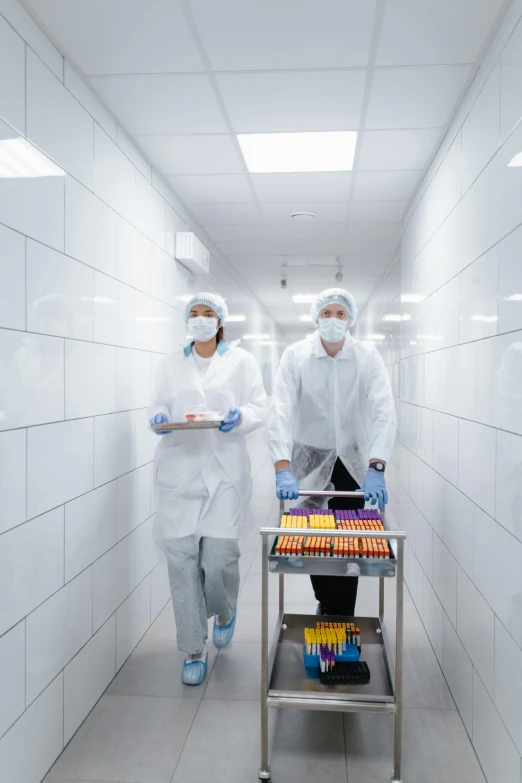 two workers in white medical suits holding trays