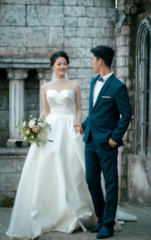 a young asian couple standing outside on their wedding day