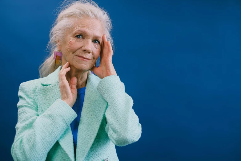 an old woman wearing a jacket and holding her hand to her face