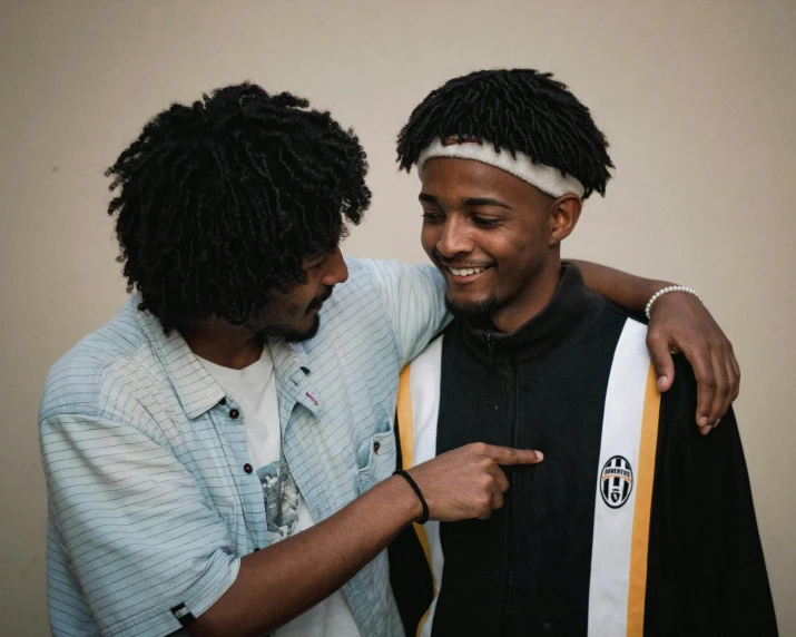 two men are posing for the camera while holding onto a jacket