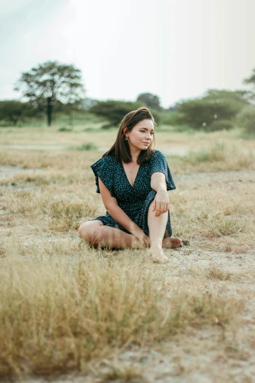 a woman squatting in the sand on a grass field